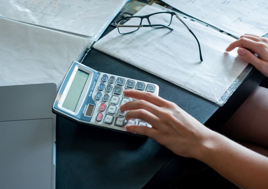 A person using a calculator on a desk, focusing on Debt Collection.