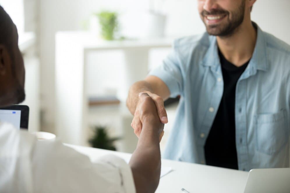 A man and another man shaking hands at a desk